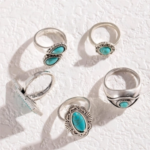 Detail of five vintage bohemian rings with turquoise stones and feather carvings on stones
