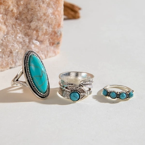 Detailed view of bohemian style feather and turquoise ring set on a natural stone background