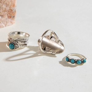 Detail of vintage silver feather ring set with turquoise beads on textured surface