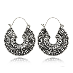 Detail of vintage bohemian silver hoop earrings with intricate hollow-out sunburst pattern