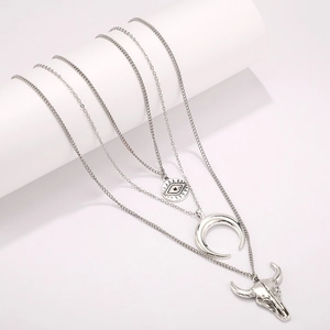 Détail du collier argenté multicouche avec pendentifs œil, lune et tête de taureau