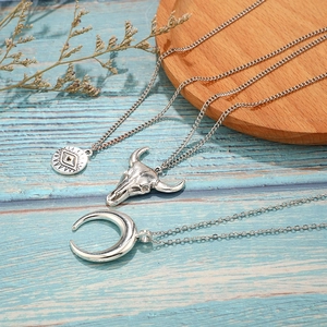 Détail du collier bohème argenté avec pendentifs tête de taureau, œil et croissant de lune