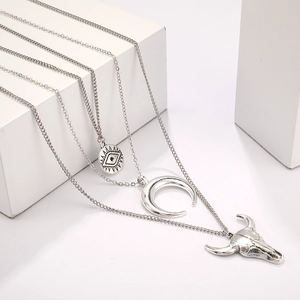 Détail d'un collier triple couche bohème argenté avec tête de taureau et breloque lune