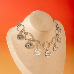 Détail du collier argenté multicouche avec pendentifs œil sur un buste beige