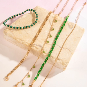Detail view of 5-piece bohemian layered anklet set with beads and green charms