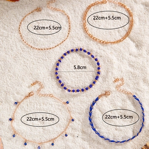 Detail shot of a 5-piece beach style anklet set with blue beads and golden shell charms