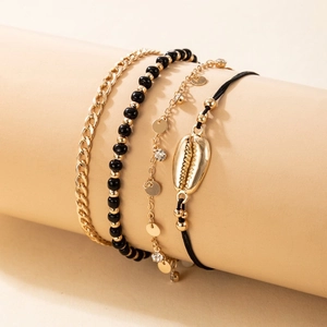 Detailed set of four bohemian anklets with gold shells, black beads, and rhinestones