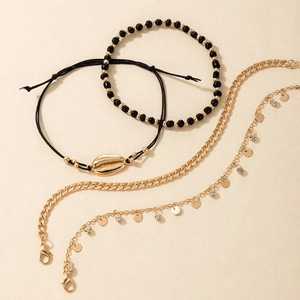 Detail of bohemian beach anklet set featuring golden shells, black beads and woven ropes