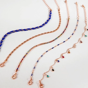 Detail of five-piece rose gold layered bracelet set with blue weaving and zircon charms