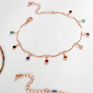 Close-up of rose gold wavy chain anklet with colorful round gemstone charms and lobster clasp