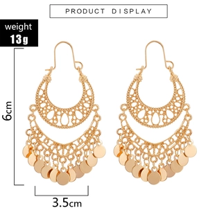 Detailed view of gold bohemian tassel earrings with hollow patterns and disc charms