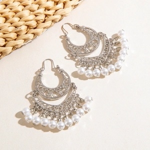 Detail of vintage silver moon earrings with white pearl tassels and hollow patterns