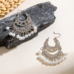 Detail of silver-finish tassel earrings with hollow crescent design and white beads