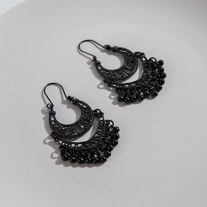 Detailed close-up of bohemian black hollow crescent earrings with beaded fringe tassels