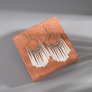 Detail of vintage silver tassel earrings with hollow lace patterns on a red stone