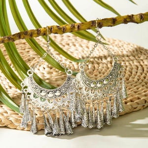 Detail of vintage bohemian silver fringe earrings with crescent patterns on palm leaf