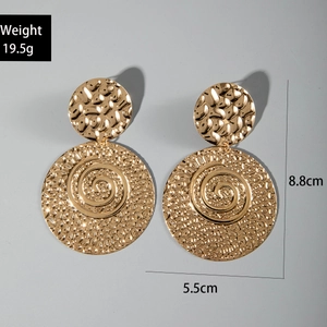 Detail of vintage golden hammered hoop earrings with spiral pattern and sizing marks
