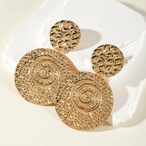 Detail of gold circular drop earrings with hammered texture and spiral design on stone