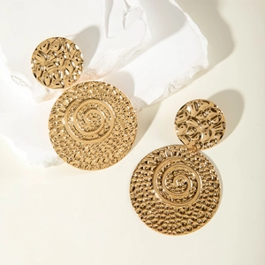 Detailed view of gold round earrings with hammered texture on white stones