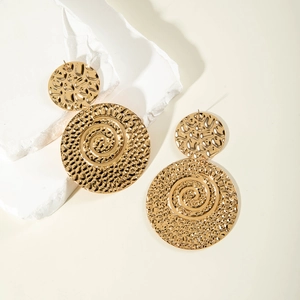 Detail of gold U-shaped tassel earrings with hammered spiral texture on white stone
