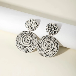 Macro shot of silver disk earrings featuring bohemian spiral relief and hammered texture