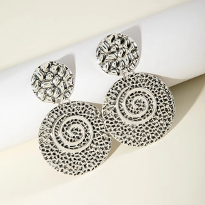 Detailed close-up of textured silver round drop earrings with hammered finish and swirls