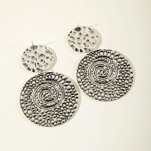 Close-up of vintage silver U-shaped earrings with spiral textures and hammered finish