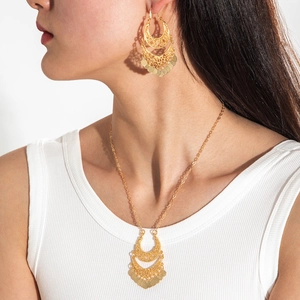 Bohemian gold hollow crescent jewelry set featuring tassel earrings and necklace on model