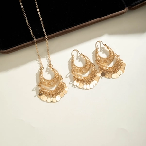 Detail of bohemian gold jewelry set with tiered crescent layers and metal coin charms