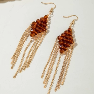 Close-up of bohemian earrings with amber faceted beads and long golden metal tassels