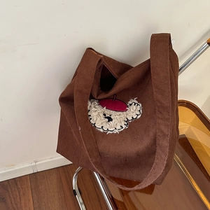 Dark brown corduroy tote bag with cute bear embroidery on an orange acrylic chair
