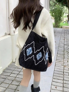 Close-up of black canvas tote bag with white wave embroidery and blue denim patchwork