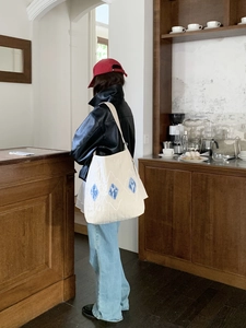 Detailed back view of model wearing cream canvas tote bag with blue diamond patterns