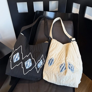 Close-up of textured shoulder bags with sawtooth embroidery and adjustable straps