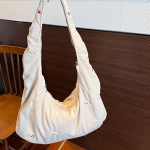 Détail du sac hobo en velours côtelé blanc cassé avec broderie de chiens colorés
