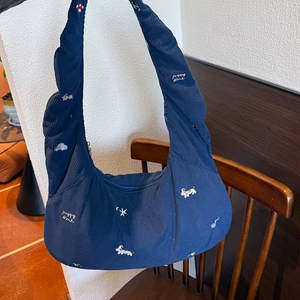 Gros plan sur le sac en velours côtelé bleu avec broderie chiot et zip