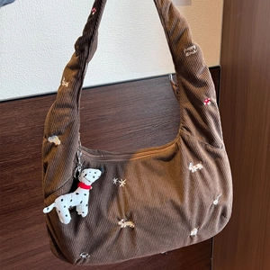 Texture détaillée du sac en velours côtelé marron avec broderie et charme de dalmatien
