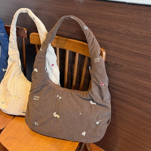 Détail de sacs à bandoulière en velours côtelé avec broderie chiot sur chaise en bois