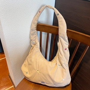 Détail du sac bandoulière en velours côtelé beige avec broderies et étiquette HOPE