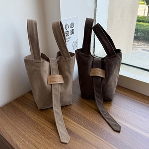 Close-up of minimalist suede tote bags in light and dark brown with leather patch detail