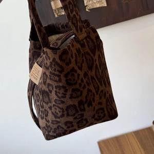 Close-up of leopard print tote bag featuring a leather brand tag and soft suede texture