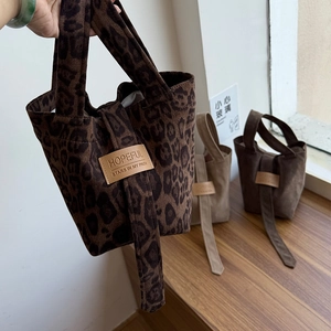 Close-up of suede tote bag featuring a vintage leather patch and animal leopard print