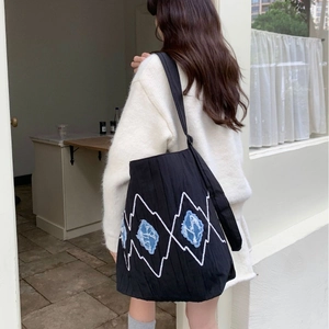 Black striped tote bag with artistic white embroidery and blue patches on shoulder