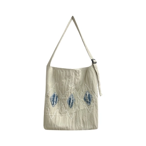 Beige pleated tote bag with blue denim diamond patches and adjustable shoulder strap