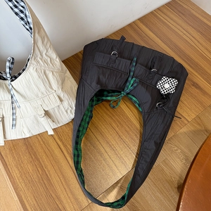 Detail of large nylon shoulder bag featuring pleated design and checkered flower charm