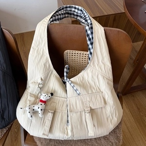 Detail of cream pleated tote bag featuring checkered lining and a cute dalmatian plush charm