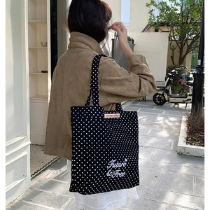 Detail of black canvas tote bag with white polka dots and Future & Free text embroidery