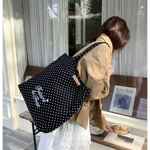 Close-up of black polka dot canvas tote bag with Future is free white embroidery detail