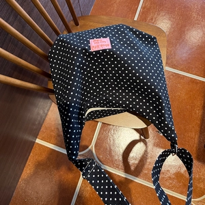 Close-up of black polka dot crossbody bag with pink patch on a wooden chair