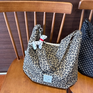 Leopard print canvas tote bag detail with plush puppy charm and minimalist white text patch